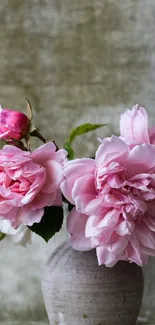 Pink roses in a vase against a rustic background.