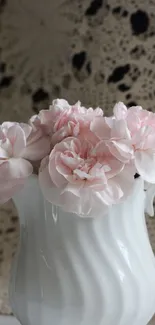 White vase with soft pink roses against crochet cloth.