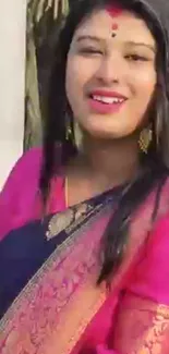 Vibrant pink saree worn by smiling woman.