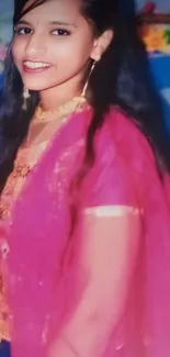 Elegant woman in a vibrant pink saree smiling gracefully.