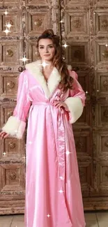 Elegant woman in pink silk robe against wooden backdrop.