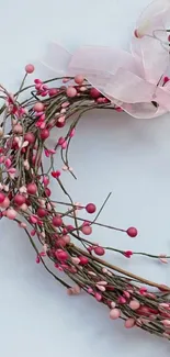 Pink wreath with delicate buds and ribbon on a white background.