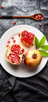 Mobile wallpaper with pomegranates on a white plate and dark textured background.