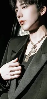 Elegant portrait of a person in a stylish suit with a gold chain necklace.