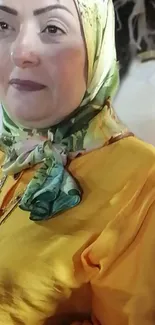 Woman wearing a green hijab and yellow outfit in a portrait.