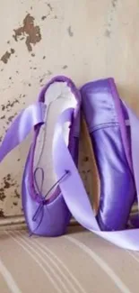 Purple ballet shoes with ribbons against a rustic backdrop.