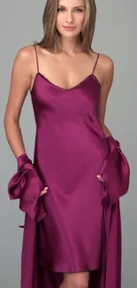 A woman in a purple satin dress poses elegantly against a gray background.