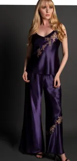 Woman in elegant purple satin pajamas on dark background.