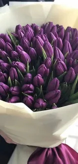 Elegant bouquet of purple tulips wrapped in white paper.