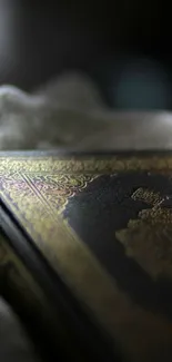 Close-up of a Quran with gold detailing on a dark, textured surface.