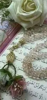 Quran open with pink prayer beads and rose on a delicate page.