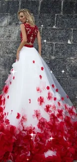 Elegant red and white gown with floral design against stone wall.