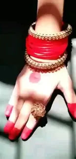 Hand wearing red bangles with intricate jewelry design.