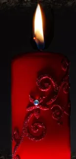 Elegant red candle glowing in the dark with intricate designs and a warm flame.