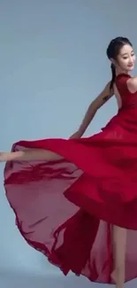 Dancer elegantly poses in a flowing red dress against a blue background.