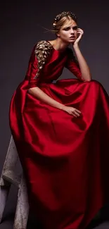 Model in elegant red gown posing on ladder with dark background.