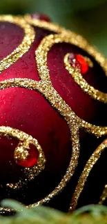 Red ornament with golden swirls on a green blurred background.