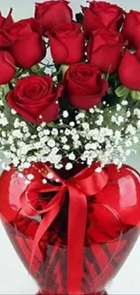 Bouquet of red roses in a glass vase with a red ribbon, on a light background.