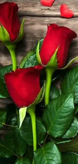 Three red roses on rustic wood background.