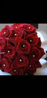 Elegant bouquet of red roses with pearl accents on a dark background.