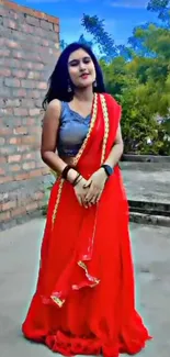 Woman in a red saree standing outdoors.