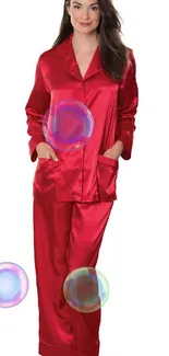 Woman in elegant red satin pajamas standing indoors.