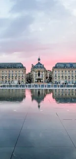 Majestic cityscape with reflective water under a pastel pink sky at sunset.