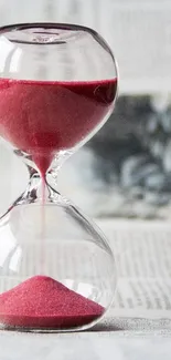 Elegant hourglass with red sand on a serene background.