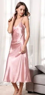 Woman in elegant pink satin dress standing in a softly lit living room.