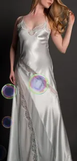 Elegant woman in satin dress with bubbles on a dark background.