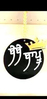 Black pendant with golden crown on chain.