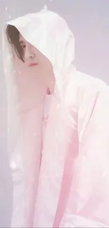 Person in a pink hooded outfit against a serene light pink background.