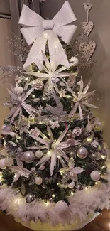 Elegant silver Christmas tree with grand bow and ornaments.