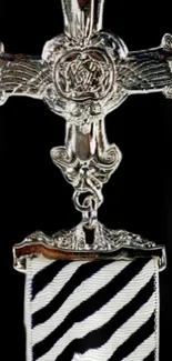 Intricate silver cross emblem with striped design background.