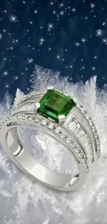 Elegant silver ring with emerald set against icy starry background wallpaper.