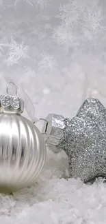 Silver Christmas ornaments on snowy background.