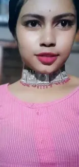 Woman wearing elegant silver necklace with pink top.