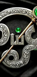 Intricate silver design with green gemstones on black background