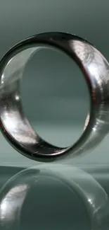 Elegant silver ring with reflection on teal background.