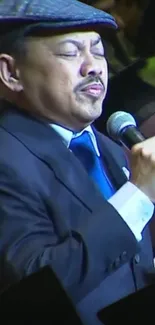 Singer in a blue suit with a hat, performing passionately on stage.