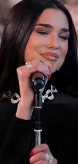 Elegant singer performs on stage with floral backdrop.