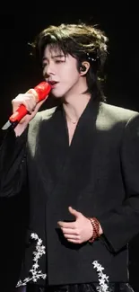 Singer on stage with red microphone and black suit.