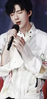 Singer in a stylish white shirt holding a microphone, performing passionately.