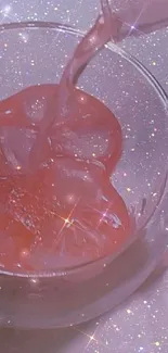 Sparkling pink drink with ice in a clear glass cup.