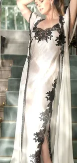 Elegant woman in a sophisticated black and white gown on a staircase.