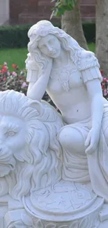 Stone sculpture of woman and lion in garden setting.