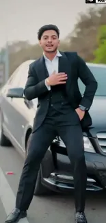 Man in black suit poses by black car on street.