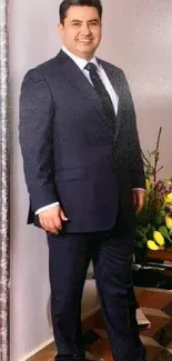 Man in a navy suit standing elegantly in wallpaper image.