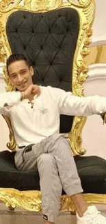 Man sitting elegantly on a luxurious gold throne.