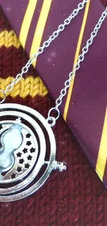 Burgundy tie and magical time turner pendant on textured knit background.